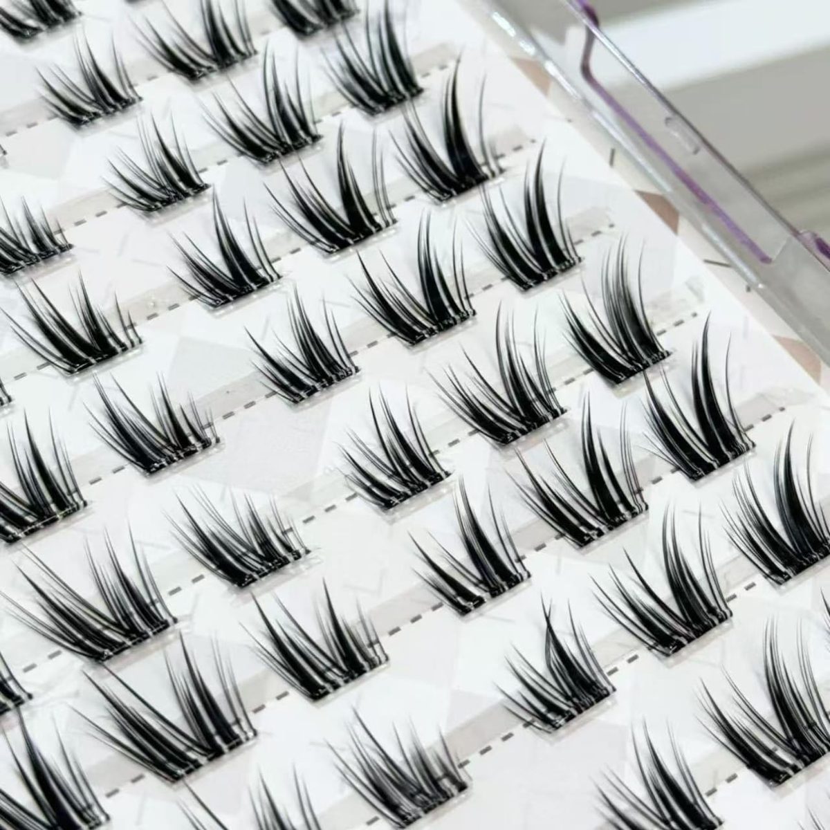 Close-up of a tray of handmade cluster lash segments